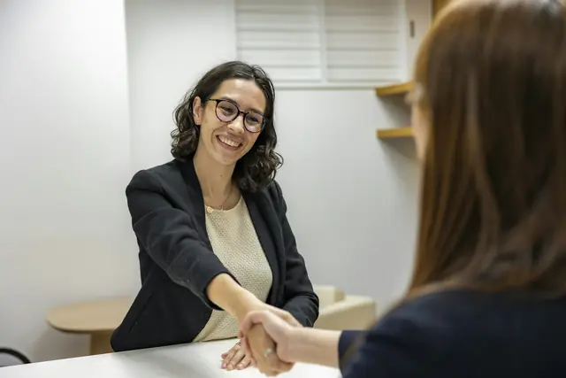 Dos personas se dan la mano en una entrevista de trabajo.